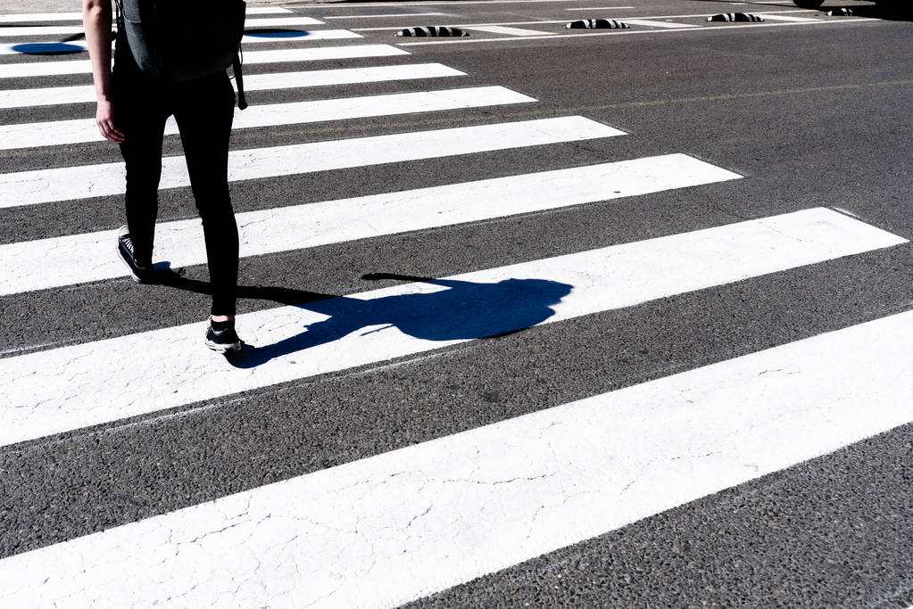 Young woman crossing a pedestrian crossing